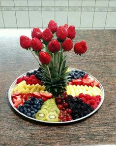 a plate filled with fruit and flowers on top of a counter next to a wall