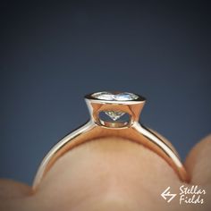 a close up of a person's hand holding a ring with a diamond on it