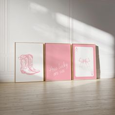 three pink and white framed pictures sitting on top of a wooden floor next to each other