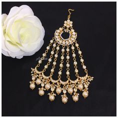 a pair of gold tone chandelier earrings with white pearls and dangling drops on the side