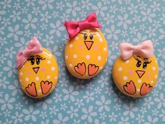 three yellow birds with pink bows on their heads are sitting next to eachother