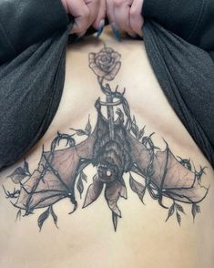 a woman's back with tattoos and roses on her stomach, showing the tattoo design