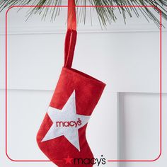 a red christmas stocking hanging from a pine tree with the word macy's written on it