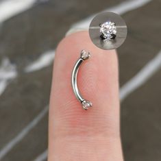 a person's finger with a nose ring and a single diamond in the middle