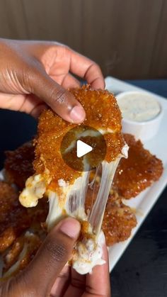 a person is holding up some food on a white plate with dipping sauce in it