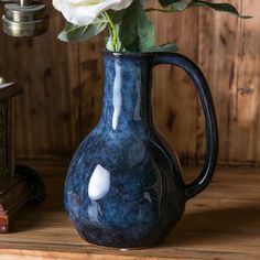 a blue vase with a white rose in it