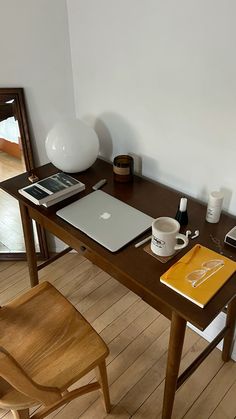 a wooden table with a laptop and coffee cup on it, next to a mirror