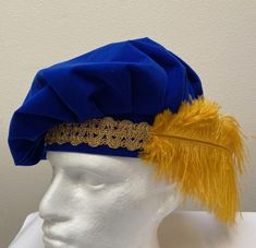 A new professional quality Renaissance Medieval Tudor muffin floppy hat. This blue velvet  fabric hat is embellished with a wide gold trim band and a gold ostrich feather.  Inside lining. New not worn.  A great accent for your Medieval Renaissance outfit for your reenactment event, theme party or stage production. All sales final but will exchange for a different size. Size X small has a 21 1/2" band Size small has a 22" band Size medium has a 22 1/2" band Size large has a 23" band Size X large has a 23 1/2" band Stage Production, Blue Velvet Fabric, Ostrich Feather, Costume Cosplay, Ostrich Feathers, Mens Costumes, Hat Cap, Blue Velvet, Velvet Fabric