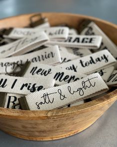 a wooden bowl filled with lots of white tags