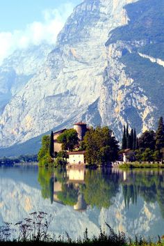 a lake with mountains in the background and houses on it's shore, surrounded by greenery