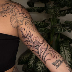 a woman's arm with flowers and words tattooed on her left arm, next to a potted plant