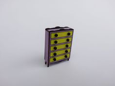 a yellow and purple dresser sitting on top of a white floor