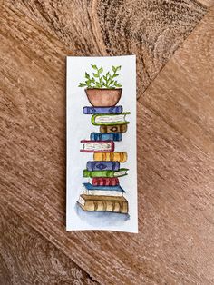 a watercolor painting of a stack of books with a potted plant on top