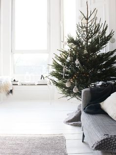 a small christmas tree in the corner of a room with white walls and flooring