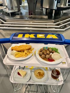 three plates with different types of food on them sitting on a cart in front of a conveyor belt