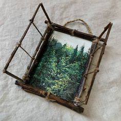 an old photo frame is sitting on a white sheet with some branches hanging from it