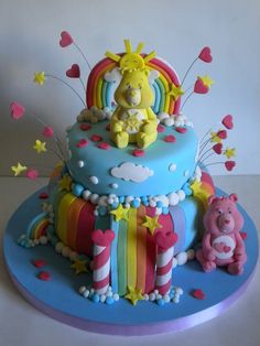 a birthday cake decorated with rainbows, stars, and hearts on a blue plate