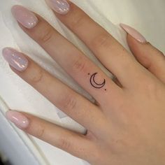 a woman's hand with a small crescent tattoo on her left ring finger,