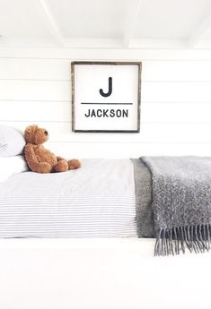 a teddy bear sitting on top of a bed in a room with white walls and wood floors