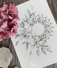 some flowers are sitting on a table next to a piece of paper with a drawing