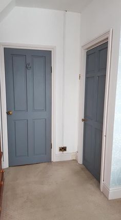 an empty room with two blue doors and a wooden bench in the corner next to it