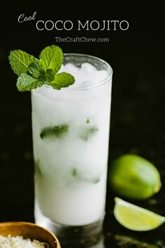 a glass filled with ice and mint on top of a table next to limes