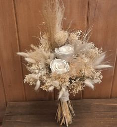 a bouquet of white flowers and feathers on a table