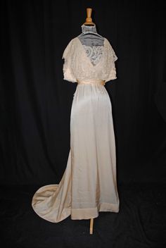 "SILK SATIN WEDDING DRESS WITH BATTENBURG LACE, TRAINED, 1920s This is an attractive Victorian wedding gown dating from 1920s is a gown that a  mid to upper class dress that a woman would wear. A regal off white gown that was deaccession from the Strong  Museum in Rochester  New York. The gown still retains original Museum ID catalog tags. The bodice is decorated with battenburg lace on front and back drop. With a high neck collar decorated with faux pearls and white beads.  Both neck collar and Historical Floor-length Wedding Gown, Floor-length Historical Wedding Gown, Historical Design Floor-length Wedding Gown, Fitted Vintage Wedding Dress With Historical Design, Wedding Evening Dress With Bias Cut, Full Length Bias Cut Gown For Wedding, Regency Style Vintage Wedding Dress With Historical Design, Elegant Vintage Wedding Dress With Historical Design, Fitted Wedding Dress With Historical Design