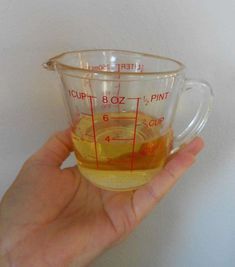 a hand holding a measuring cup filled with liquid