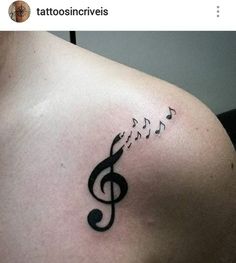 a musical note tattoo on the back of a woman's left shoulder and chest