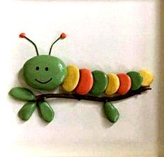 a green and yellow caterpillar sitting on top of a white wall mounted plaque