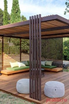 an outdoor seating area with wood slats and green cushions on the deck, surrounded by trees