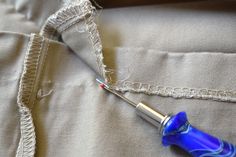 a blue and silver pen laying on top of a white cloth next to a piece of fabric