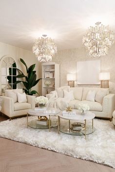 a living room with white furniture and chandeliers