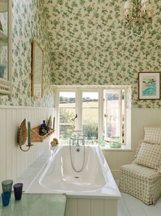 a bath tub sitting under a window next to a chair