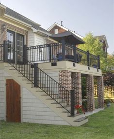 a brick house with black wrought iron railings and stairs leading up to the second story