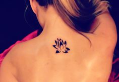 the back of a woman's neck with a lotus tattoo on it