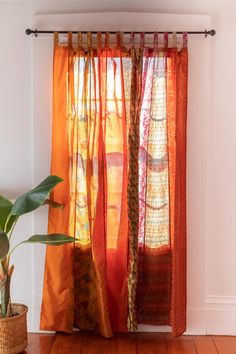 an orange curtain hanging on the side of a wall next to a potted plant