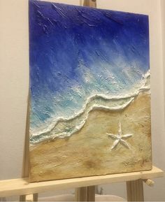 an easel with a painting on it that has a starfish in the sand