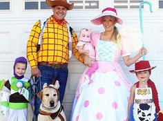 a man and woman in costume standing next to two children, one with a dog