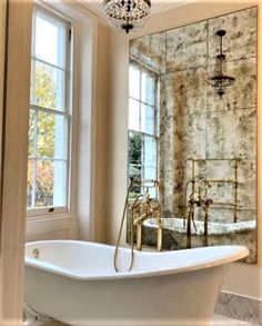 a bath tub sitting next to a window with a chandelier hanging above it