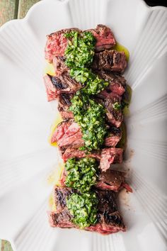 a piece of steak with pesto on it sitting on top of a white plate