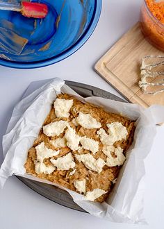 some food is sitting on a table next to a bowl and cutting board with utensils