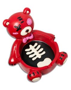 a red bear with a bone in it's mouth sitting on top of a black plate