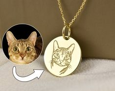 a cat's face is shown on a gold plated necklace with an arrow