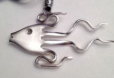 a metal fish on a black cord with a silver hook in the shape of a mouse