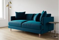 a blue couch sitting on top of a hard wood floor next to a table and lamp