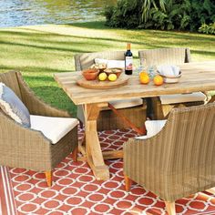 an outdoor dining table with chairs and fruit on it in front of a grassy area