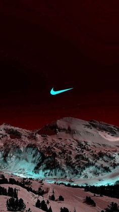 the sky is red and black with a green nike logo on top of snow covered mountains