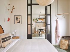 a white bed sitting under a window next to a wooden table